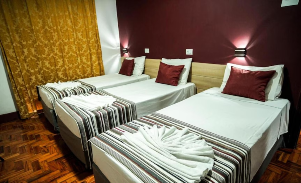 Hotel para excursões em Poços de Caldas: O guia completo para viagens em grupo e eventos corporativos 3 Quarto confortável e organizado do Euro Suite, ideal para hospedagem para grupos em Poços de Caldas, com camas macias e iluminação acolhedora
