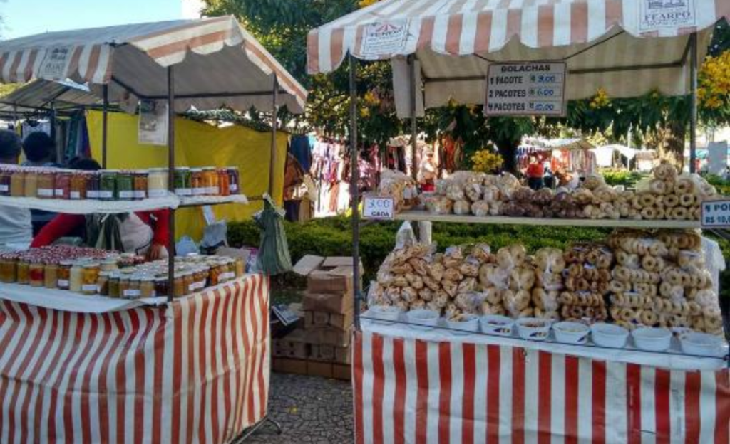 Roteiro Econômico em Poços de Caldas: Guia Definitivo para Viajar Gastando Pouco 4 Bancas de artesanato e doces típicos na feira de domingo em Poços de Caldas, representando opções de compras baratas