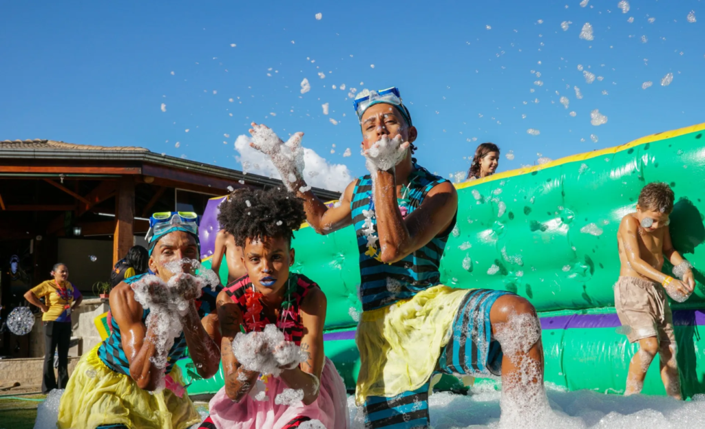 A Experiência Definitiva em um Resort All Inclusive em Poços de Caldas para Famílias 3 Crianças brincando com monitores na área verde do Cassino Resort em Poços de Caldas