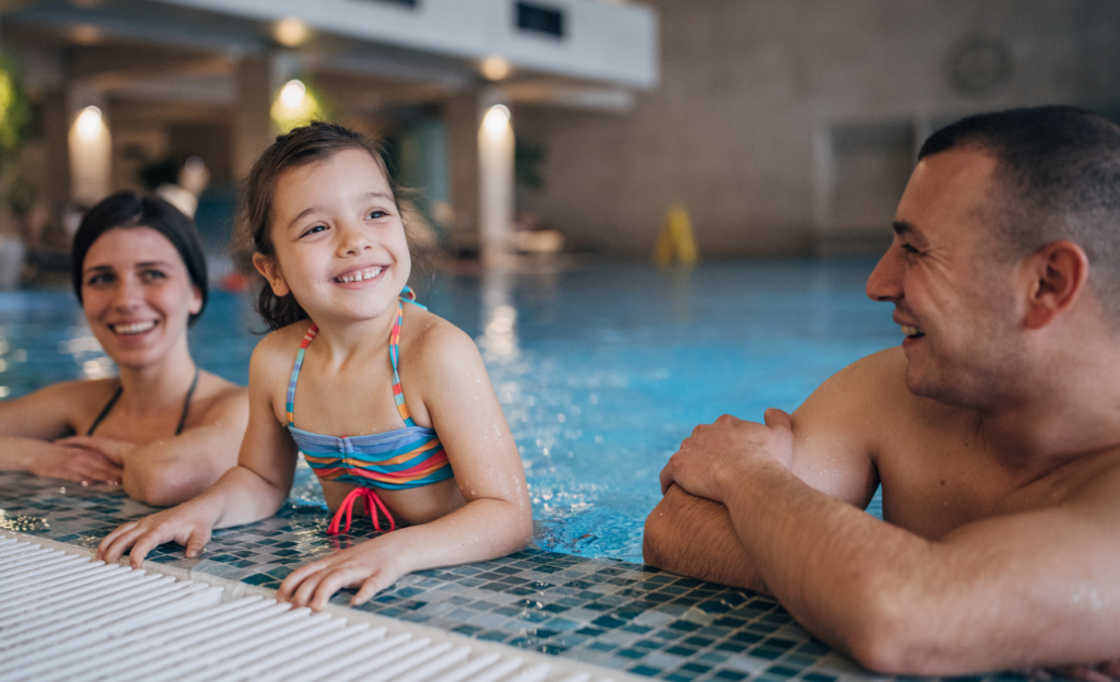 Cassino All Inclusive Resort: O Guia Definitivo para Seu Inverno em Poços de Caldas 3 Família se divertindo na piscina coberta e aquecida do Cassino All Inclusive Resort, com vapor subindo da água e vista para as janelas embaçadas pelo frio externo