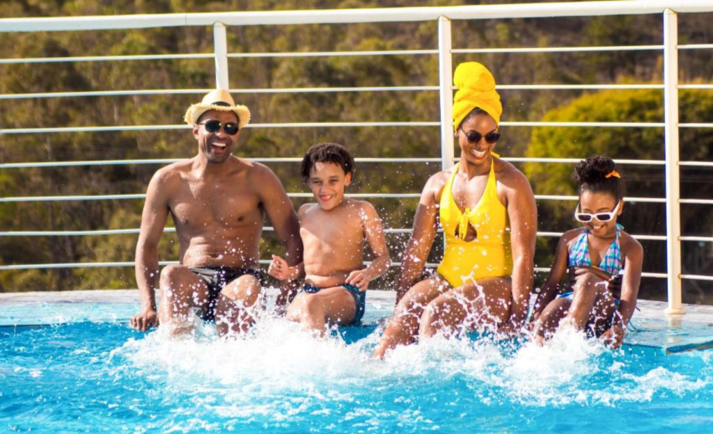 A Experiência Definitiva em um Resort All Inclusive em Poços de Caldas para Famílias 2 Família sorrindo na piscina do resort all inclusive em Poços de Caldas com montanhas ao fundo