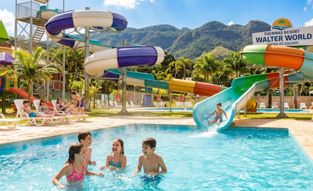 Piscinas Aquecidas em Resort: Por Que São o Segredo das Melhores Férias em Poços de Caldas 4 Crianças brincando em piscina aquecida com toboágua no Thermas Resort Walter World, com paisagem verde de Poços de Caldas ao fundo