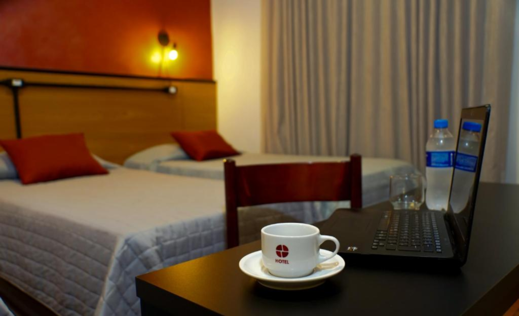 Hotel Corporativo em Poços de Caldas: como o Euro Suite é a base ideal para reuniões estratégicas e hospedagem de equipes 3 Apartamento do Euro Suite Poços de Caldas com bancada de trabalho iluminada, laptop aberto e ambiente organizado para home office corporativo