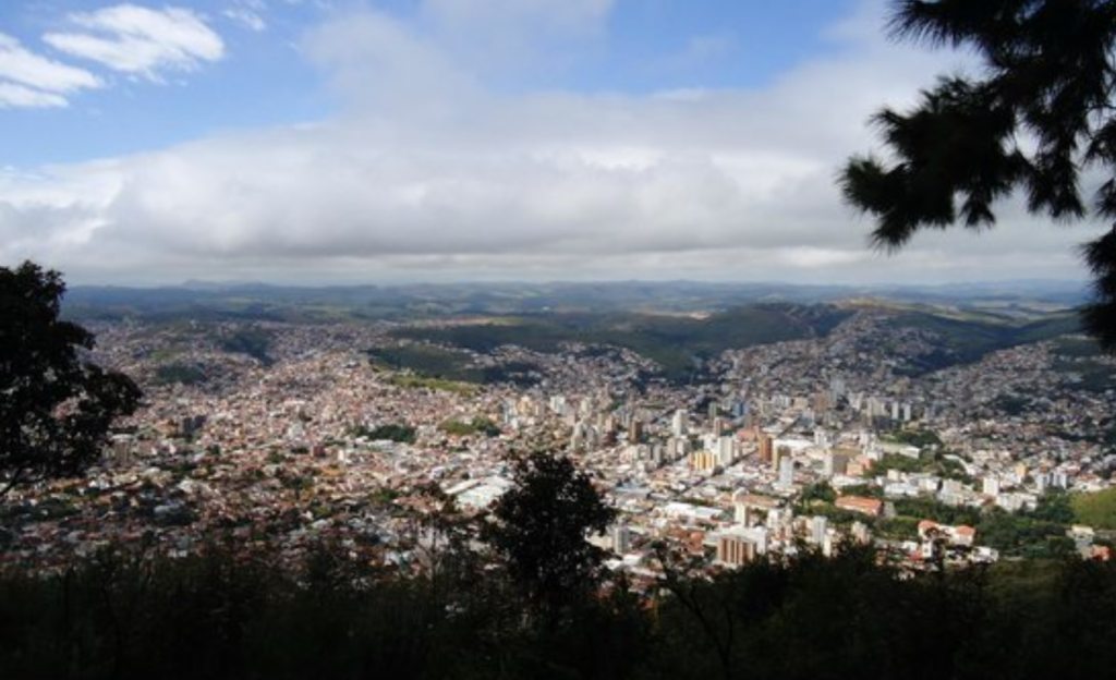 Hotel com sala de eventos em Poços de Caldas: infraestrutura que resolve para encontros corporativos até 80 pessoas 4 Vista panorâmica do centro histórico de Poços de Caldas ao entardecer com a Serra de São Domingos ao fundo e arquitetura característica da cidade