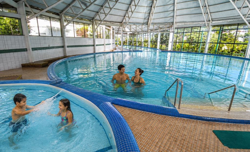 Hotel em Poços de Caldas para família: a viagem que resolve todo mundo com um único endereço 4 Pais e crianças brincando em área de lazer coberta durante dia frio em Poços de Caldas